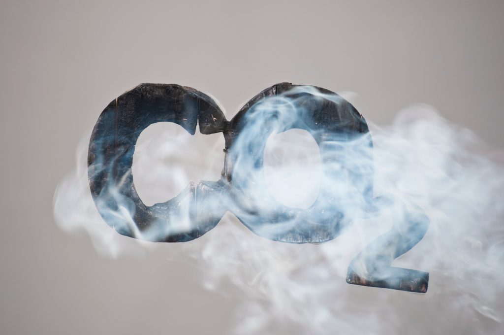 Teksten CO2 i sort som det ryker av. Grafisk illustrasjon.