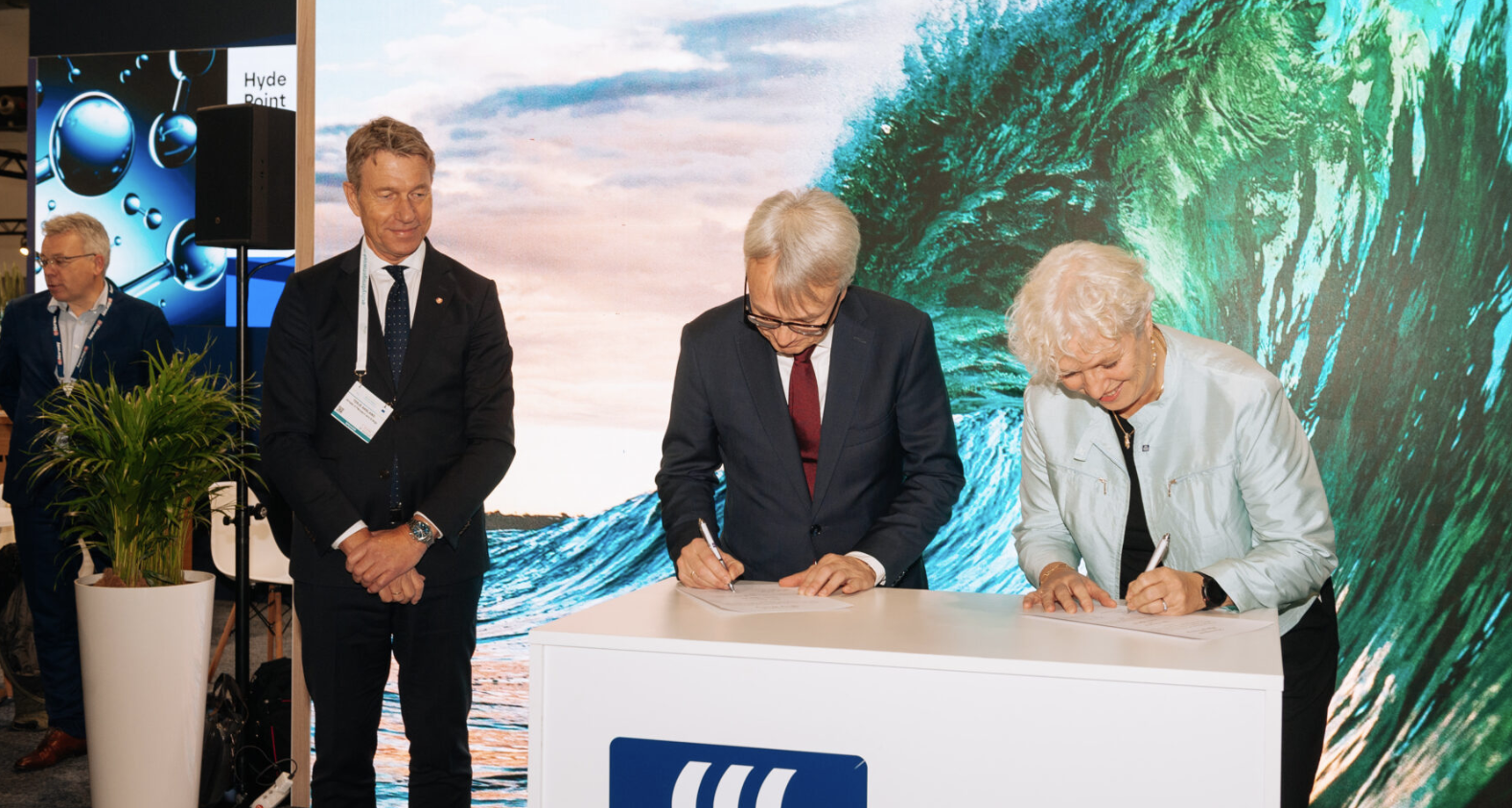 En kvinne og mann som signerer en avtale, mens en minister ser på. Bilde